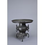 A JAPANESE BRONZE TWO-HANDLED TRIPOD CENSER. With removable flat-topped liner above a baluster