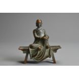 A JAPANESE MEIJI PERIOD (1868-1912) SMALL BRONZE MODEL OF A RAKAN SEATED ON A BENCH. Cast clasping