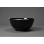 A LARGE CHINESE BLACK GLAZED PORCELAIN BOWL, 20TH CENTURY. Heavily potted round bowl covered in a