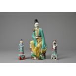 THREE CHINESE GLAZED PORCELAIN FIGURES, 20TH CENTURY. A figure of Guanyin holding a lotus spray with