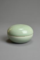 A CHINESE PALE CELADON GLAZED BOX AND COVER, 19/20TH CENTURY. Of circular form with four character