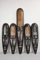 FIVE LARGE DECORATIVE HARDWOOD AFRICAN TRIBAL STYLE MASKS INLAID WITH MOTHER OF PEARL AND COINS.