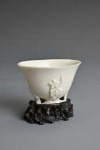 A CHINESE BLANC DE CHINESE PORCELAIN LIBATION CUP, 17TH CENTURY. With applied floral sprays on an