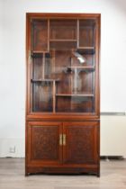 A CHINESE ROSEWOOD AND GLASS DISPLAY CABINET, 20TH CENTURY. Two piece cabinet with a two doored