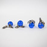 CARTIER Lot of 4 silver figurines in the shape of a panther sitting or lying on a round blue glass b