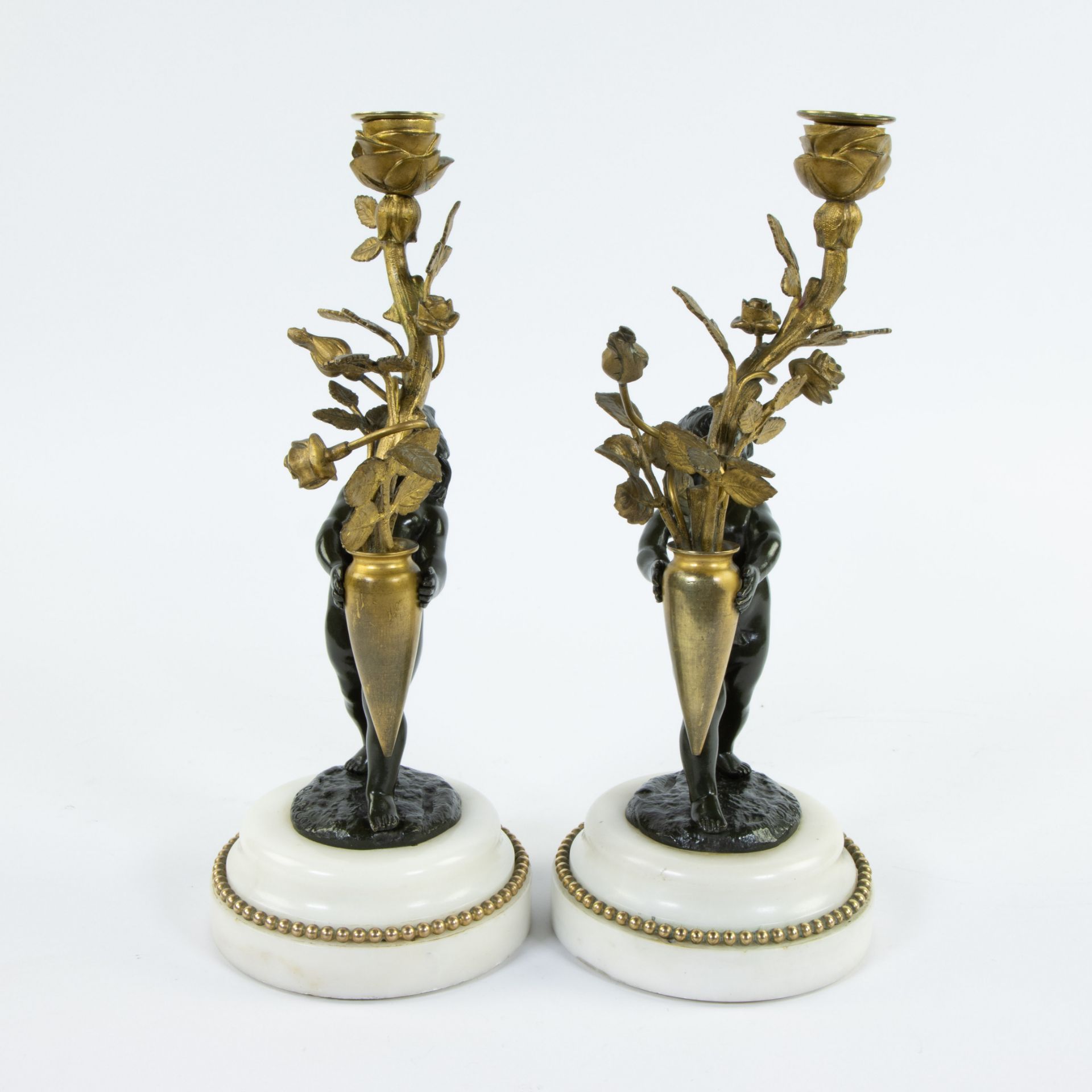 Pair of candlesticks gilded stem as light point carried by brown patinated bronze children on white - Image 2 of 5