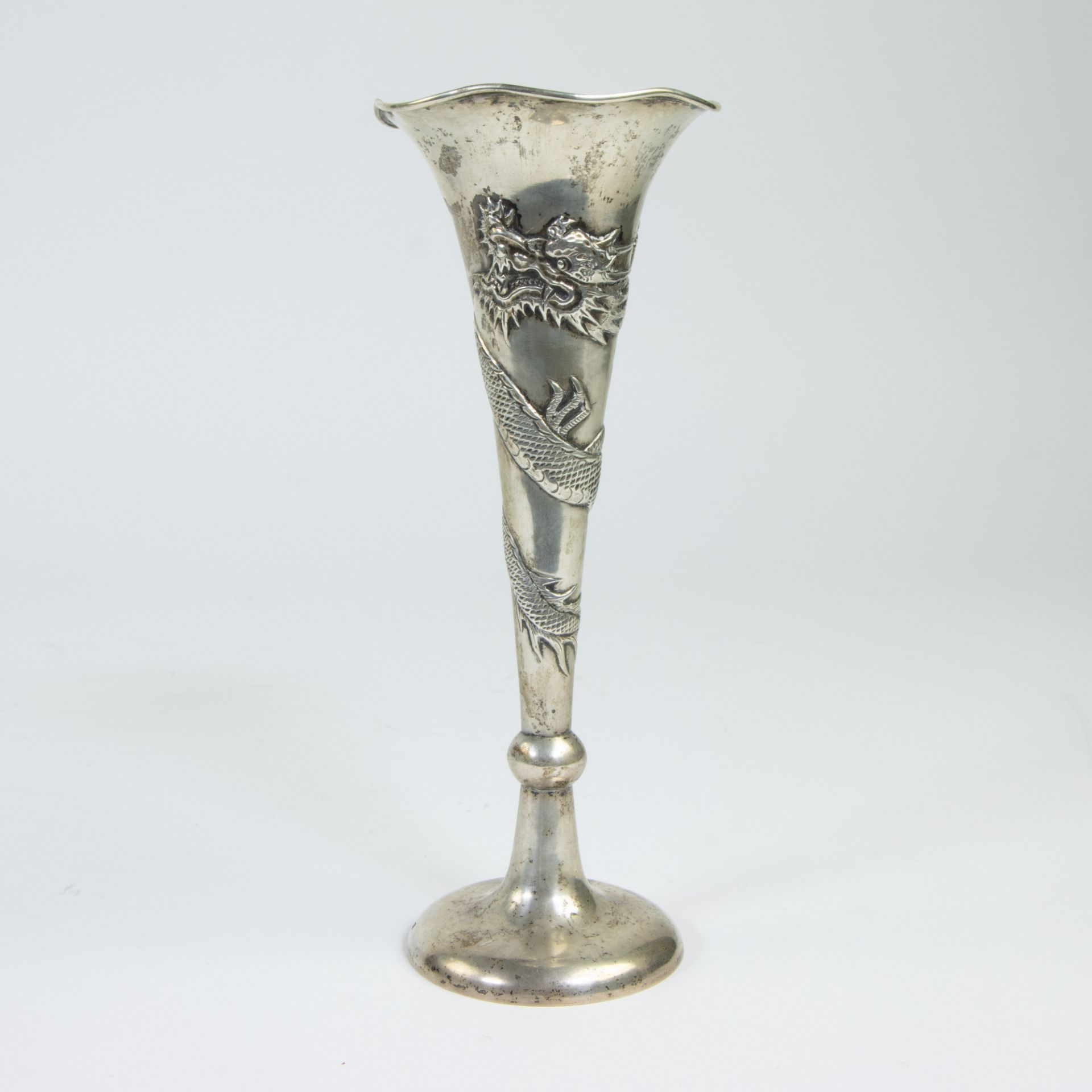 A silver Chinese soliflore vase decorated with a dragon chasing the sacred pearl.