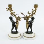 Pair of candlesticks gilded stem as light point carried by brown patinated bronze children on white