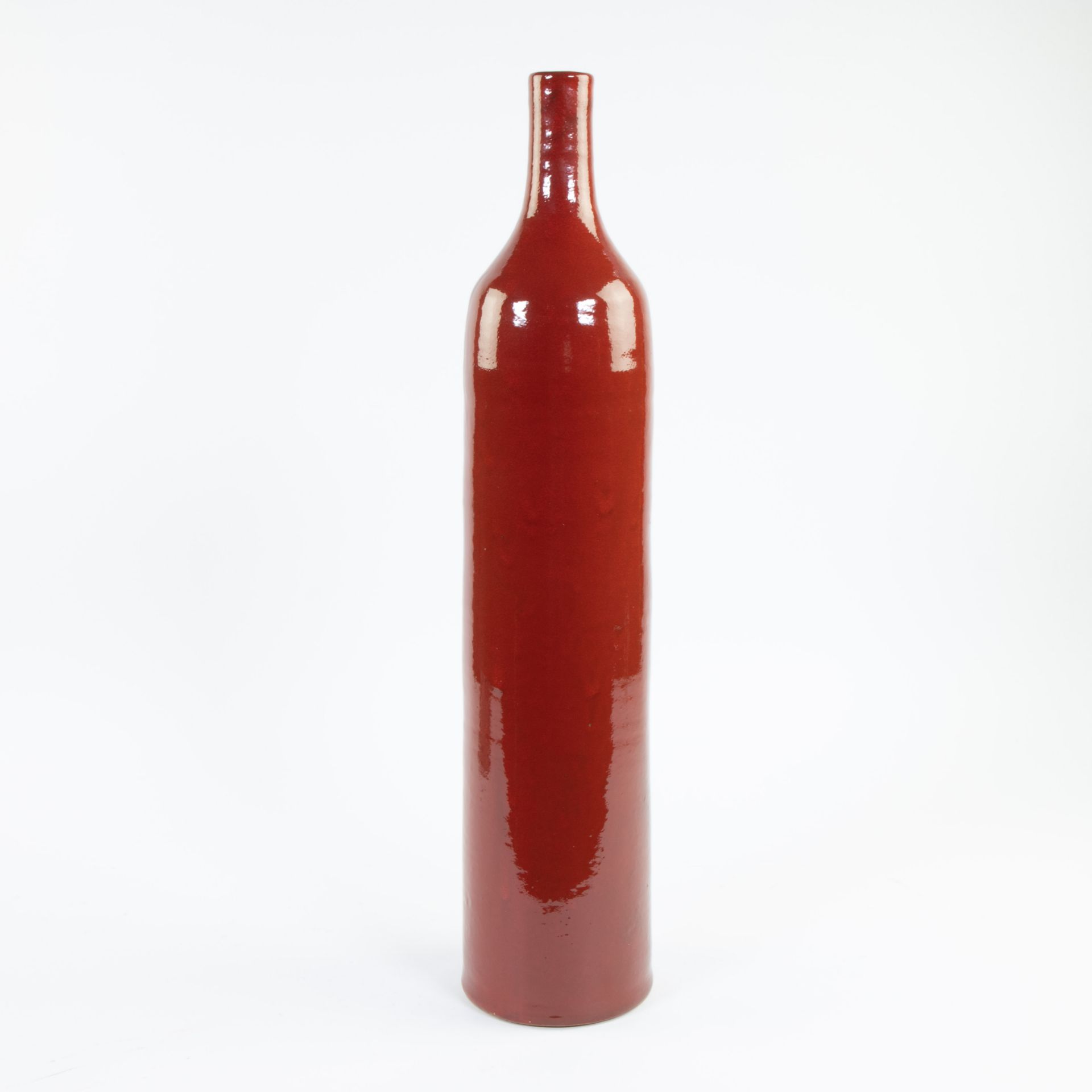 Tall tightly stylised red glazed ceramic vase