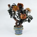 Cloisonné pot with gilt fittings, containing a bush of peonies, the leaves carved from serpentine, t