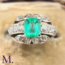 An Emerald and Diamond Ring The 18ct white gold ring is set with a bright green emerald cut