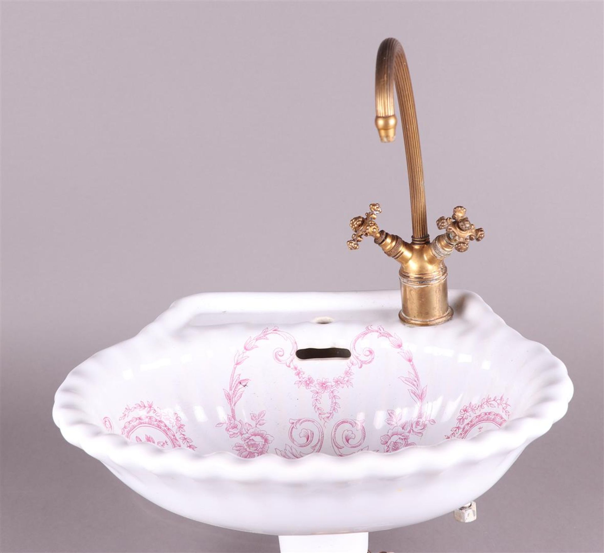 An earthenware sink decorated with flowers and a brass faucet. Early 20th century.
