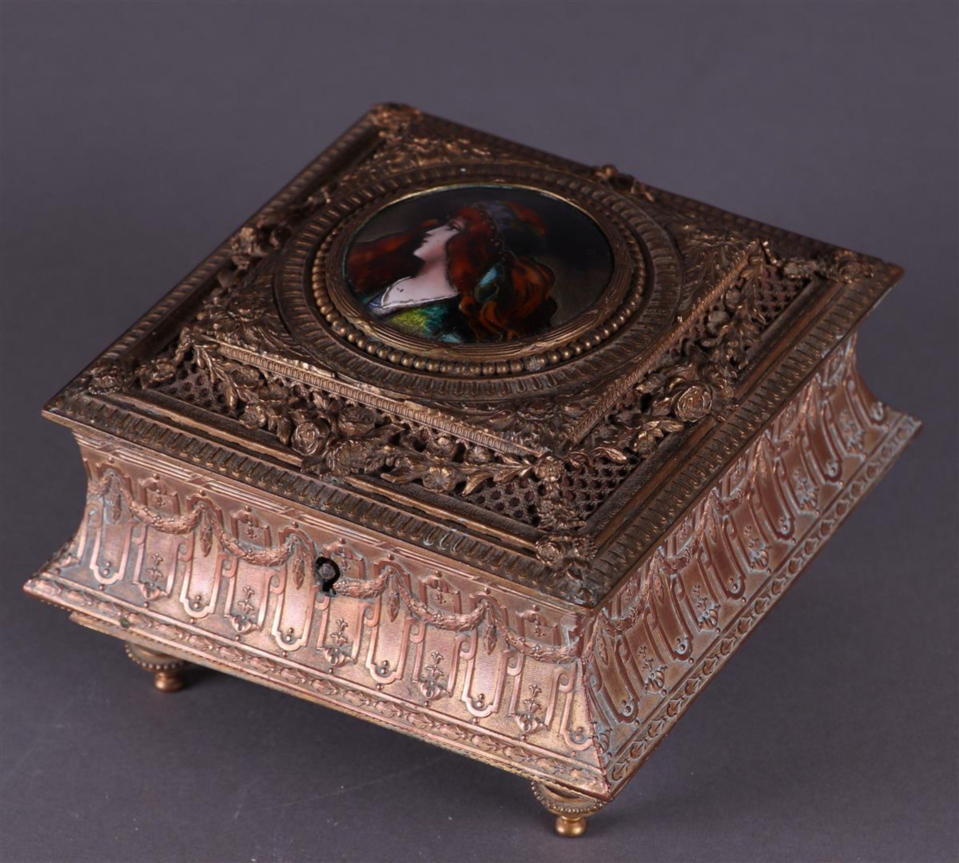 An Art Nouveau, brass jewelery box with enamel plaque of a young woman. about 1880.