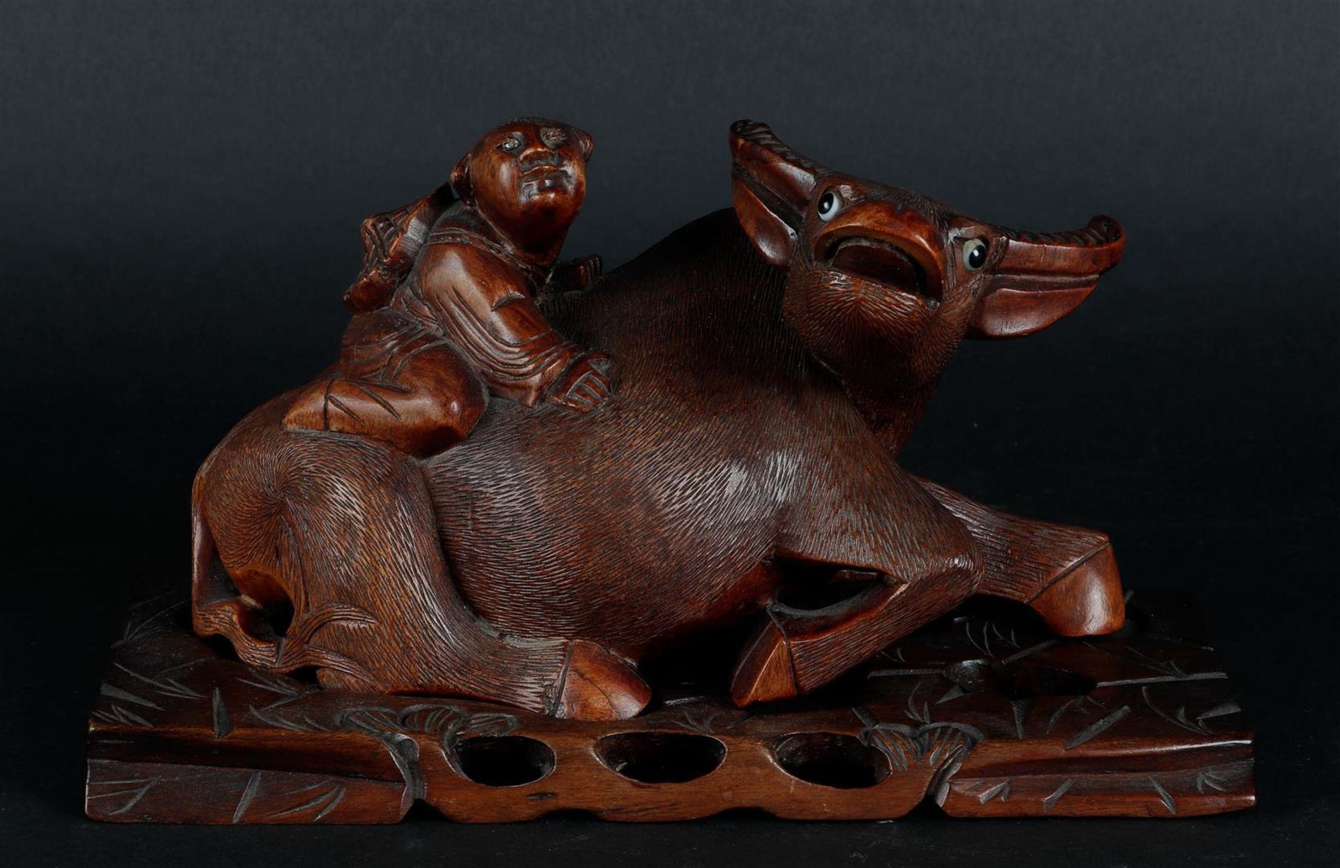 A wooden sculpture of a Chinese boy on a water buffalo, on a wooden base. China, 20th century.