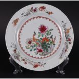A porcelain Famille Rose plate with two peacocks in rich floral decoration,
