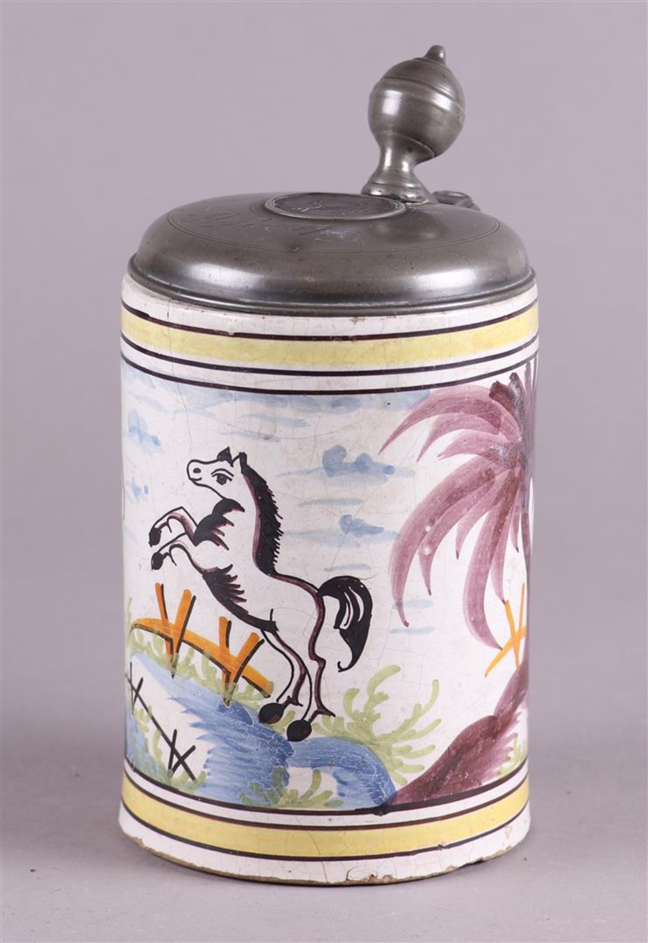 An earthenware beer jug with a polychrome decor of a rearing horse, with a pewter lid.