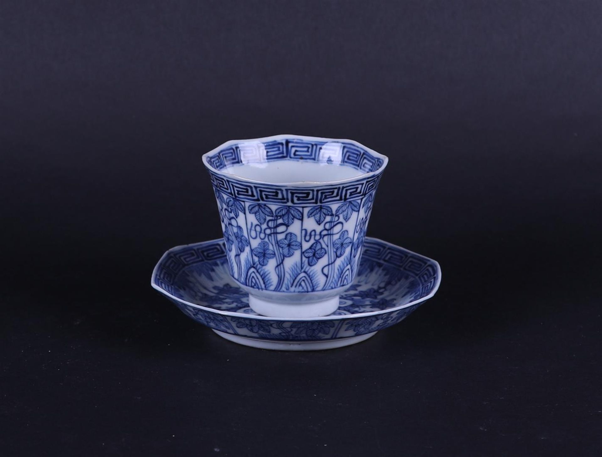 A porcelain 8-sided cup and saucer with floral decor in borders