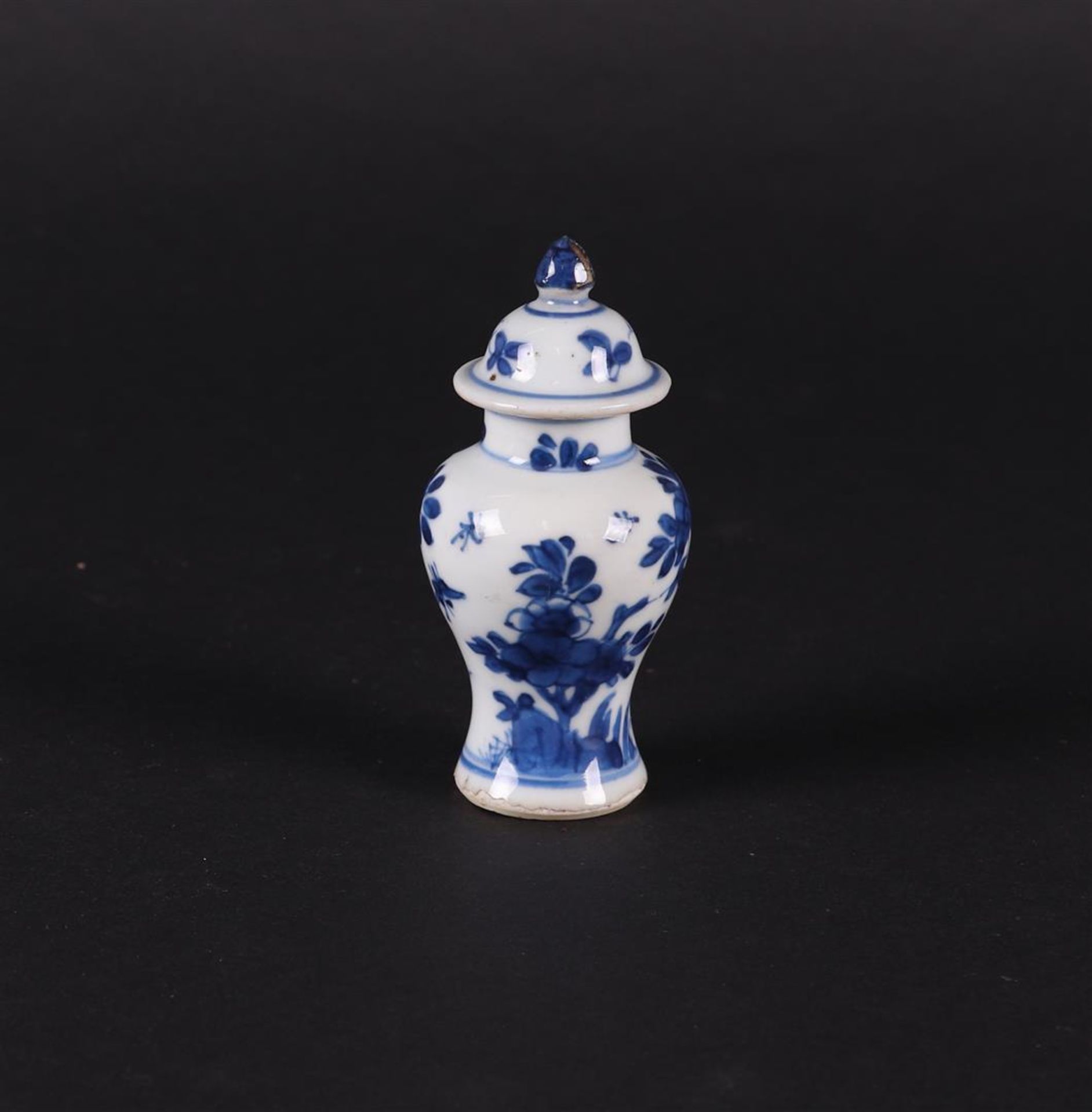 A porcelain baluster-shaped lidded vase with a rich floral decoration with insects in between.