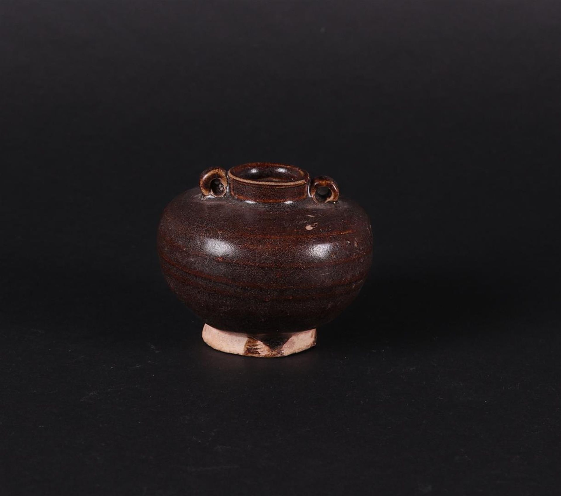 A brown stoneware storage jar with two looped ears. China early Ming.