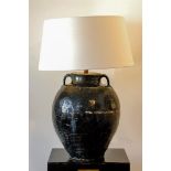 A large black-glazed lamp with a white shade.