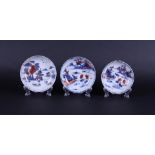 Three porcelain Imari plates with decoration of a riverlandscape with boats and a pagoda.