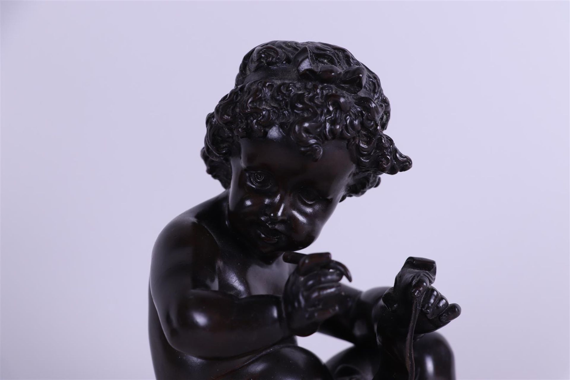 A brown patinated bronze of a writing putto. 19th century. - Image 4 of 5