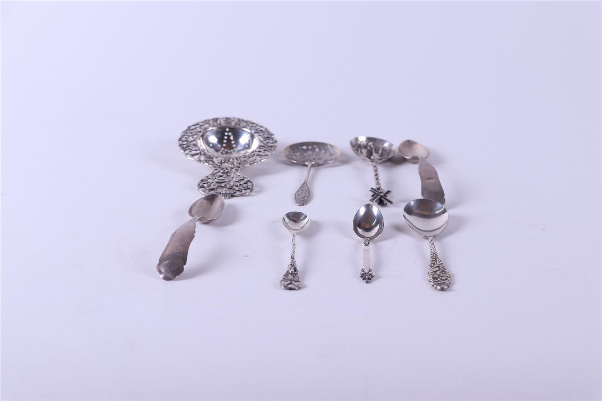 A lot comprising (8) various silver objects including a tea strainer, two shakers, a sugar spoon,