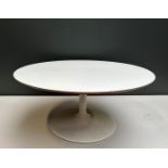 A round coffee table with white round top, inspired by Earo Saarinen.