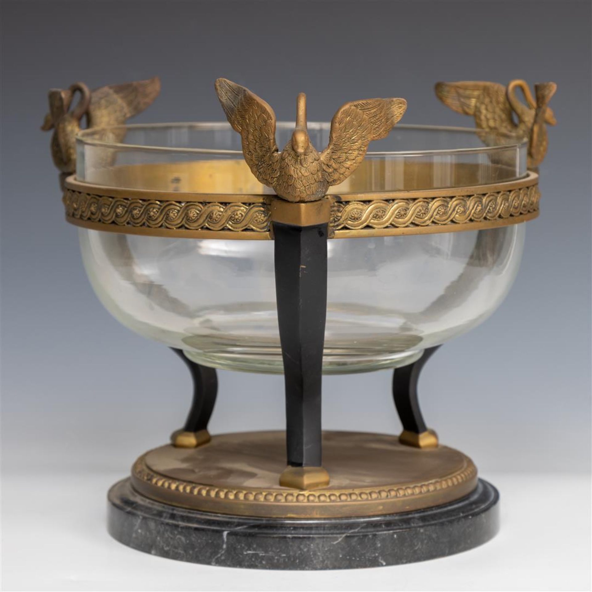 A glass coupe worn by a brass frame with swans.