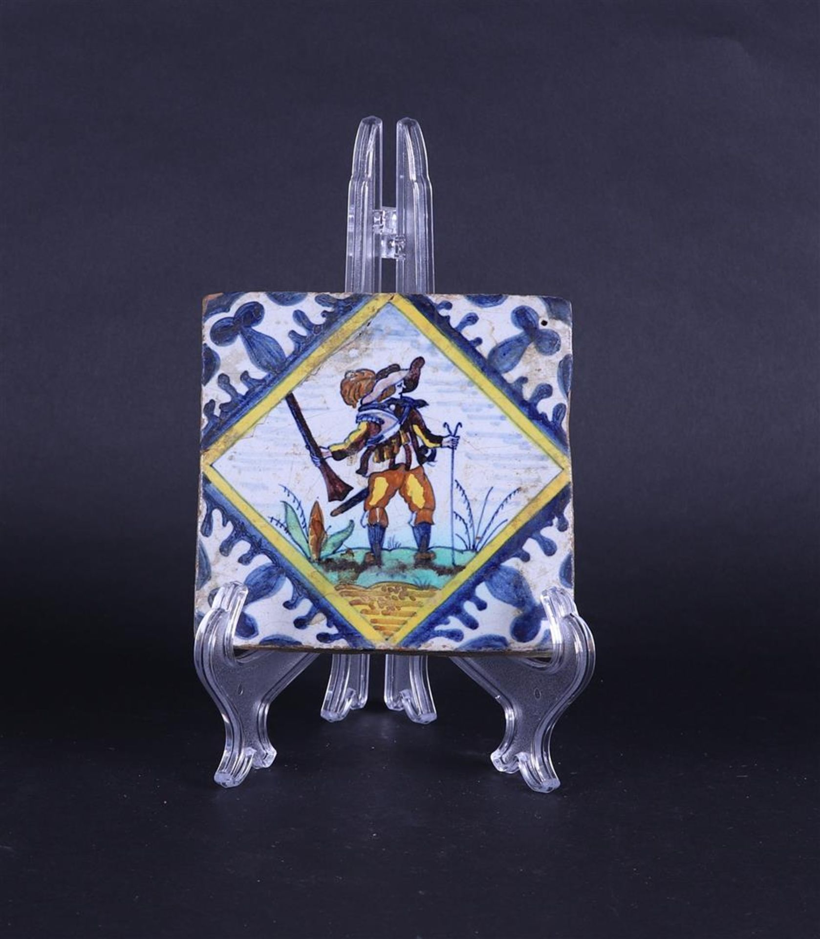 A polychrome earthenware tile depicting a soldier with a musket in a landscape 