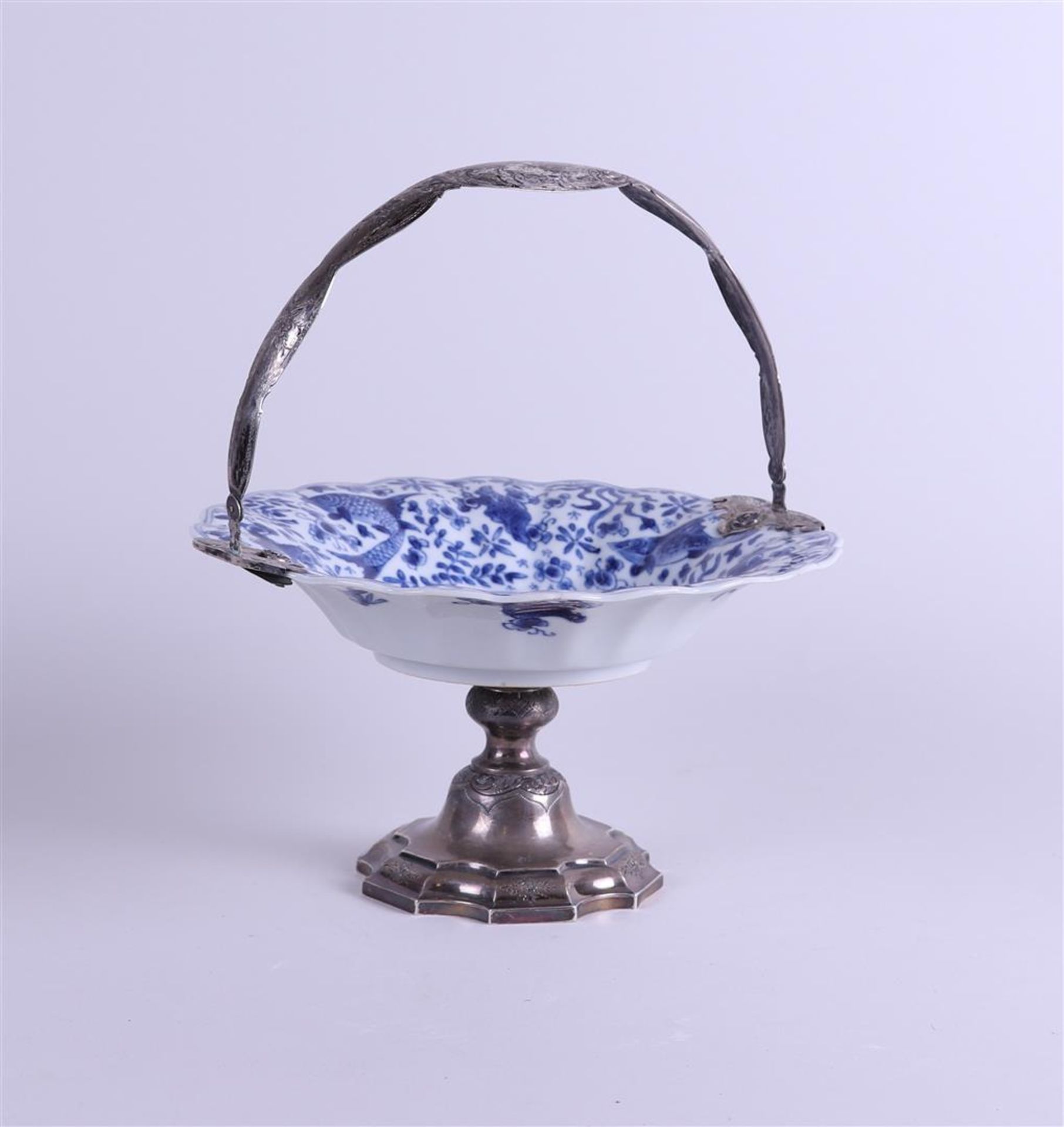 A lobed porcelain dish decorated with fish, on a 19th century silver foot and ditto handle. 