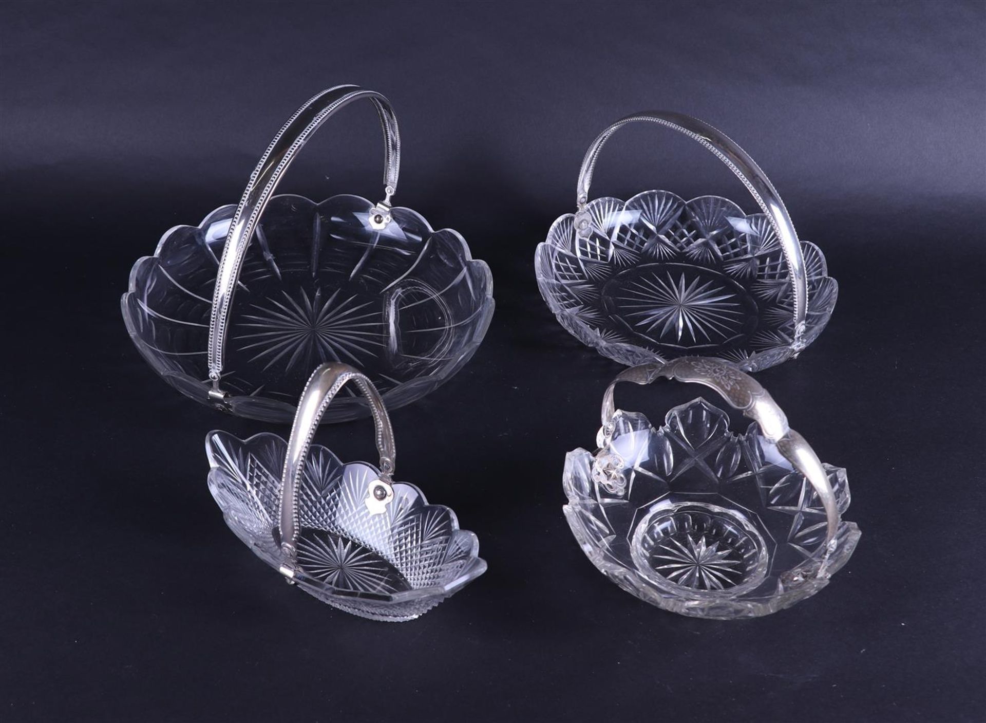 A lot of four chrystal bowls and baskets with silver handles. Early 19/20th century. 178 grams.