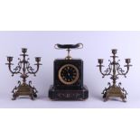 A black marble mantel clock with two brass three-armed candlesticks. Circa 1900.