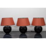A lot consisting of (3) black glazed lamps with blood red shade.