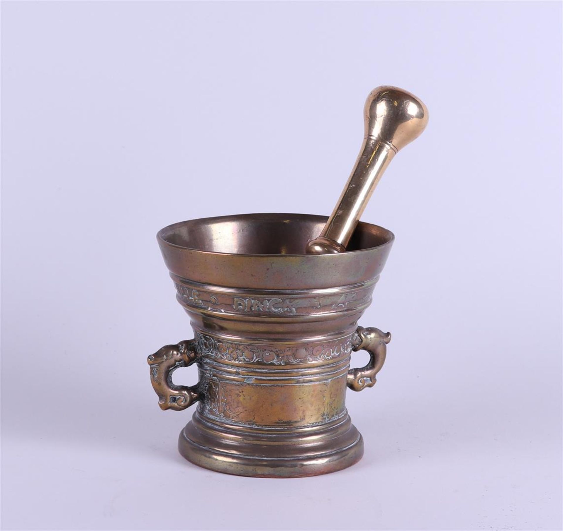 A bronze mortar with inscribed pestle; Love Verwindt alle Dingk A. 1629.<