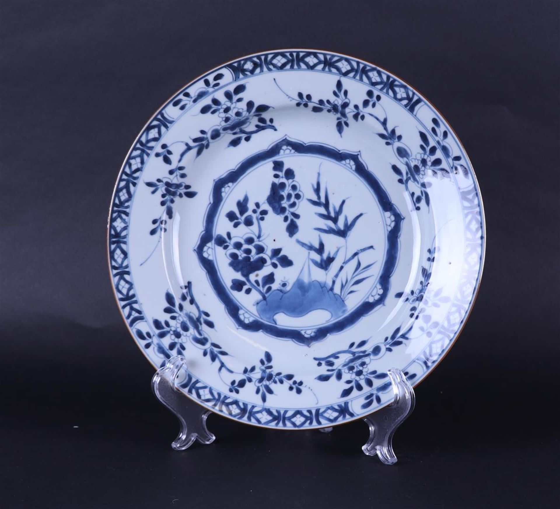 A porcelain dish with floral decoration in the center and with a diamond/box outer edge. 