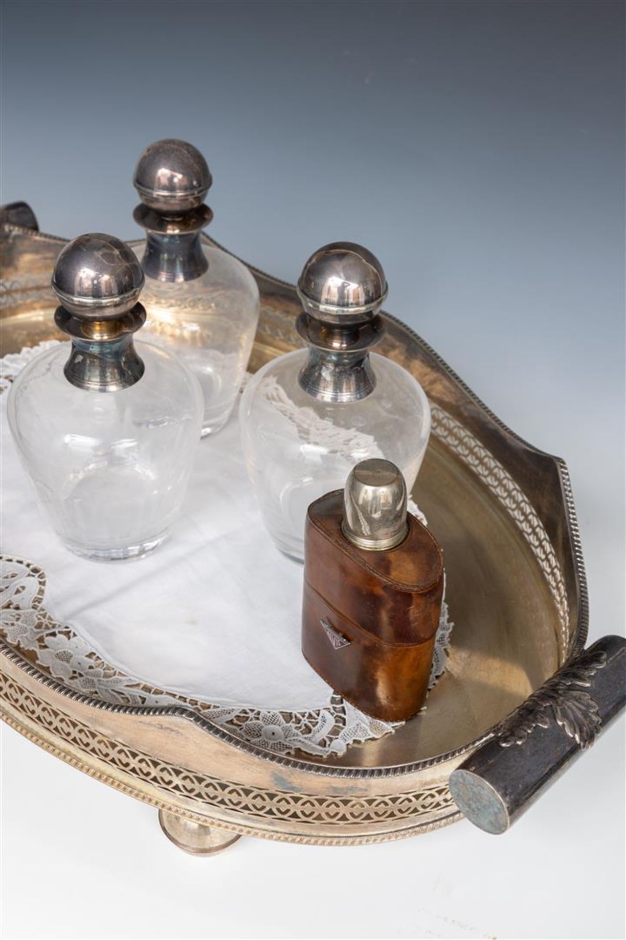 A lot consisting of a silver-plated tray, three decanters, and a liquor bottle in a leather case.