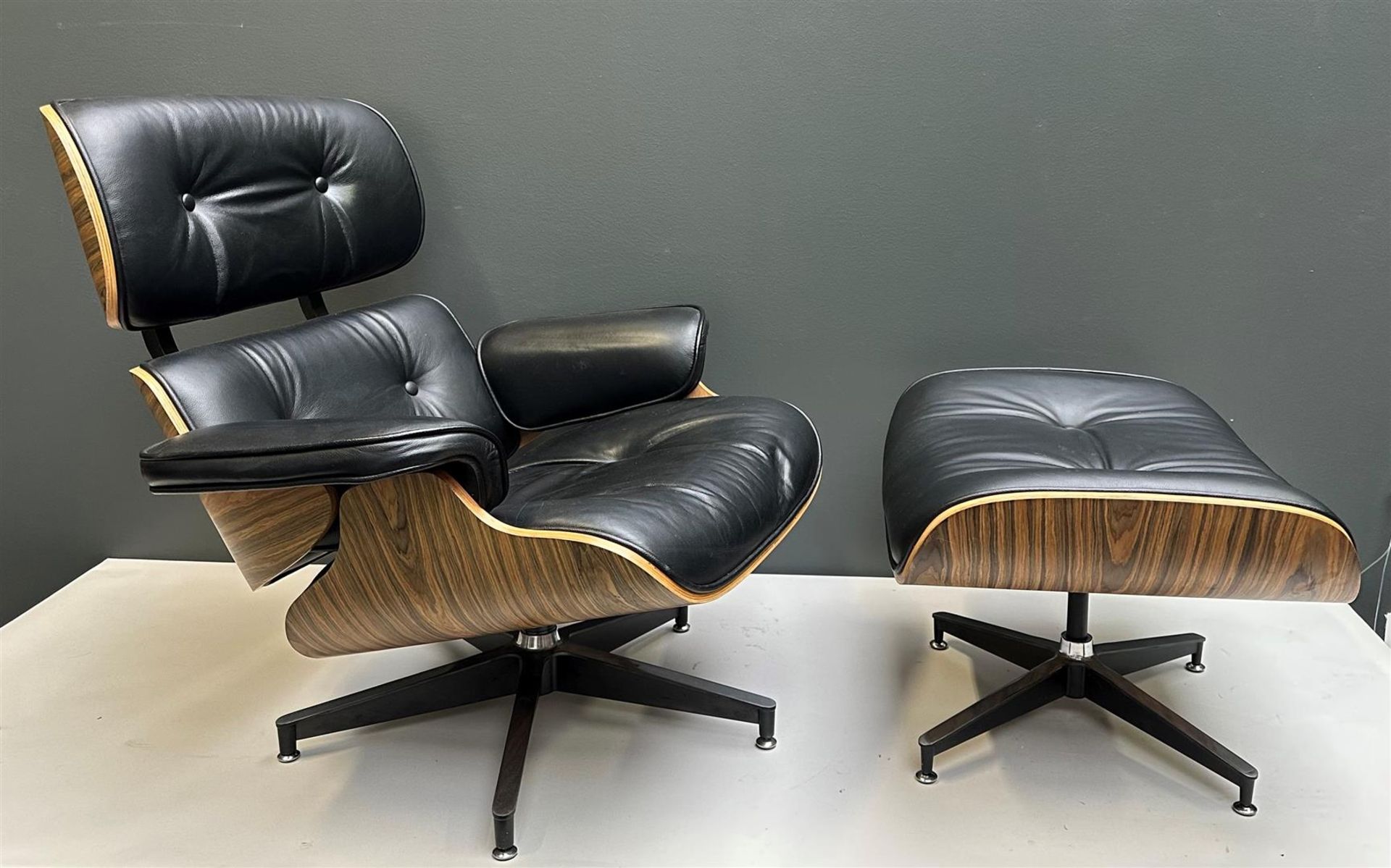 A black leather designer chair with ottoman inspired by Charles & Ray Eames 