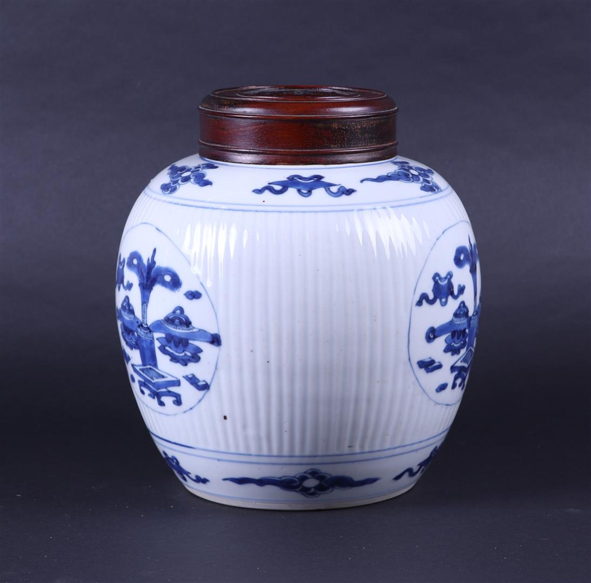 A large ribbed porcelain ginger jar decorated with various antiques and a wooden lid. China, Kanxi. - Image 4 of 7