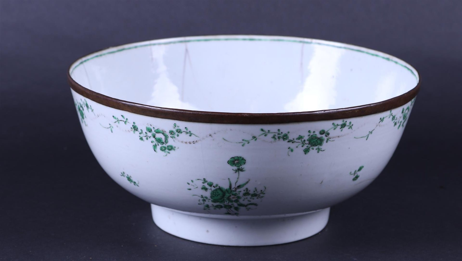 A large porcelain Chine de Commande bowl with a green decoration of flowers, copper ring on rim. 