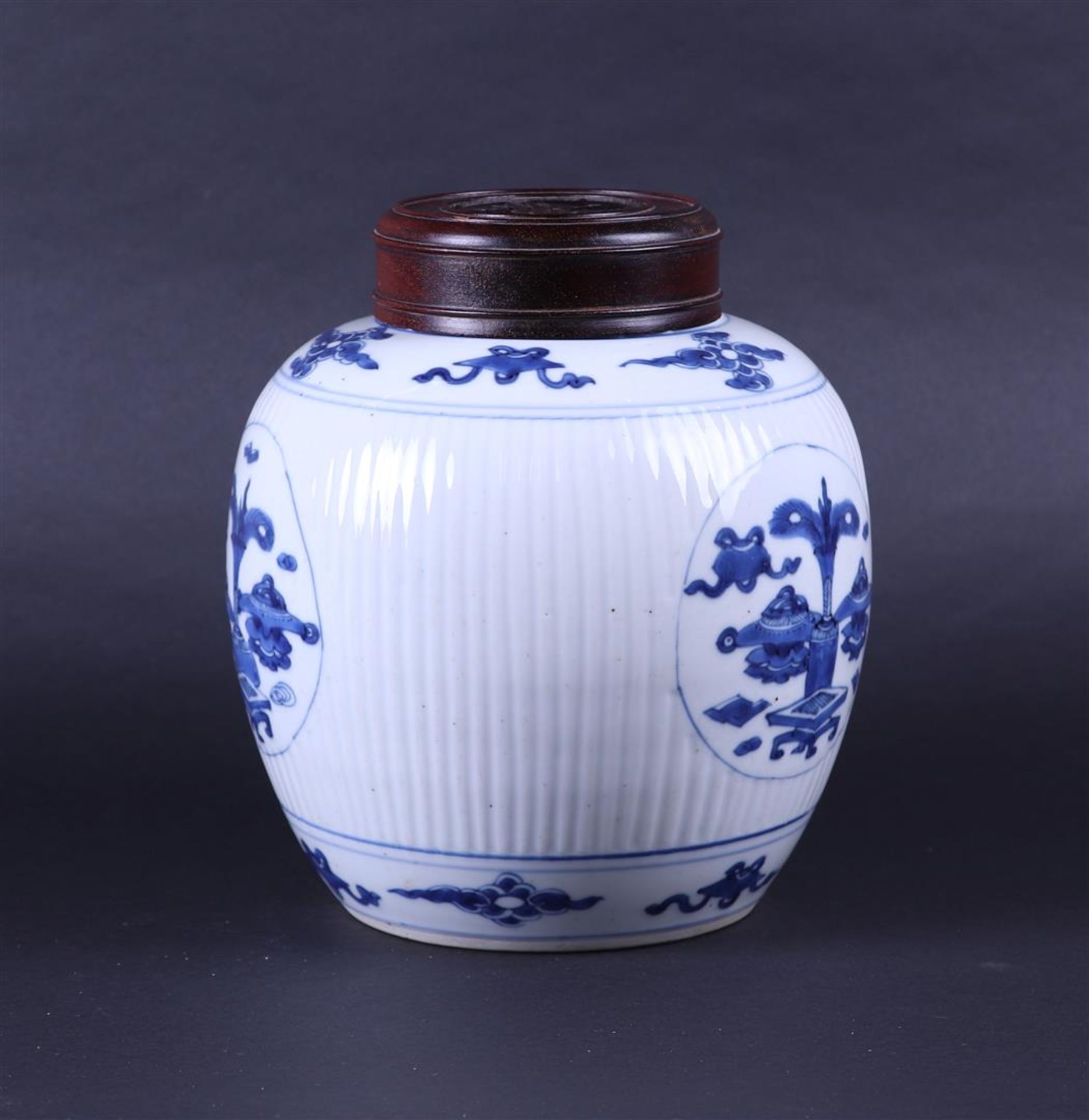 A large ribbed porcelain ginger jar decorated with various antiques and a wooden lid. China, Kanxi. - Image 2 of 7