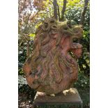 A terra cotta garden ornament in the shape of a lion's head. Mounted on plinth.