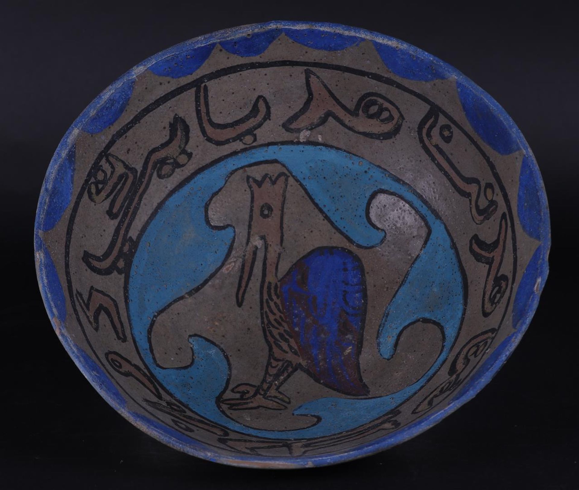 An earthenware Nishapur bowl with floral decor and decorated in the center with a fable figure. 