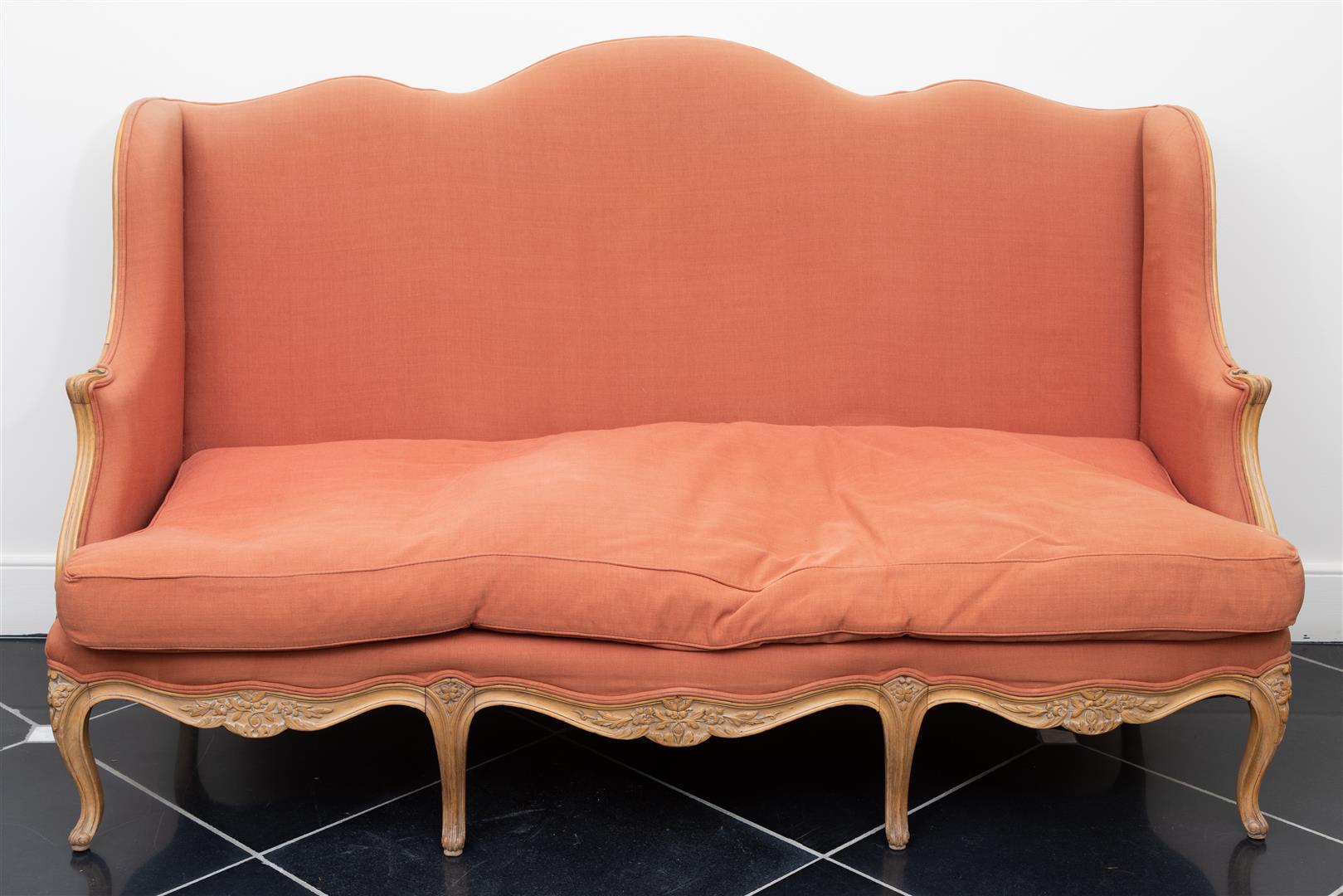 A Louis XV style settee upholstered in red fabric.
