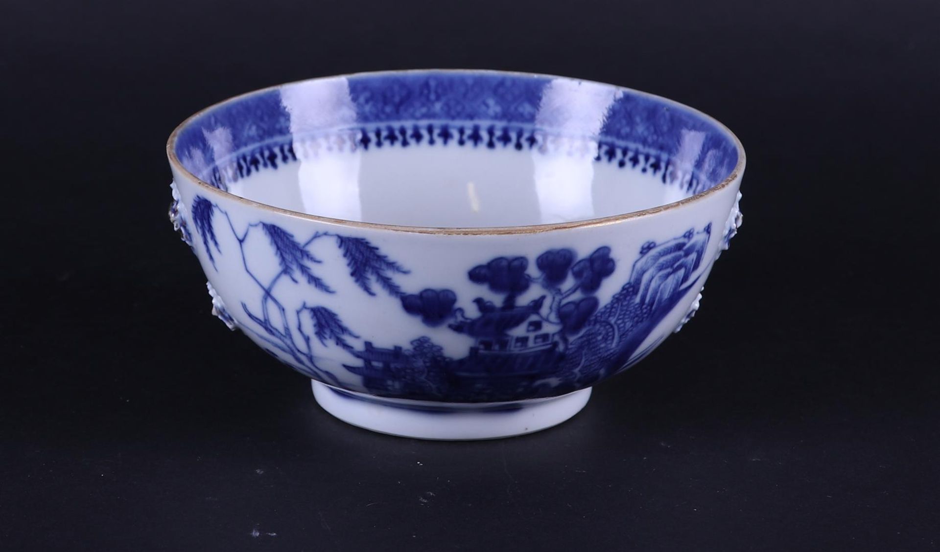 A porcelain bowl with river landscape decor on the outside and embossed flowers on the outside. 