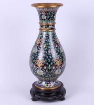 A cloisonne vase on a wooden base with floral decor. China, 20th century.