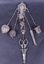 A silver chatelaine with scissors, a finger hold and various other attributes.