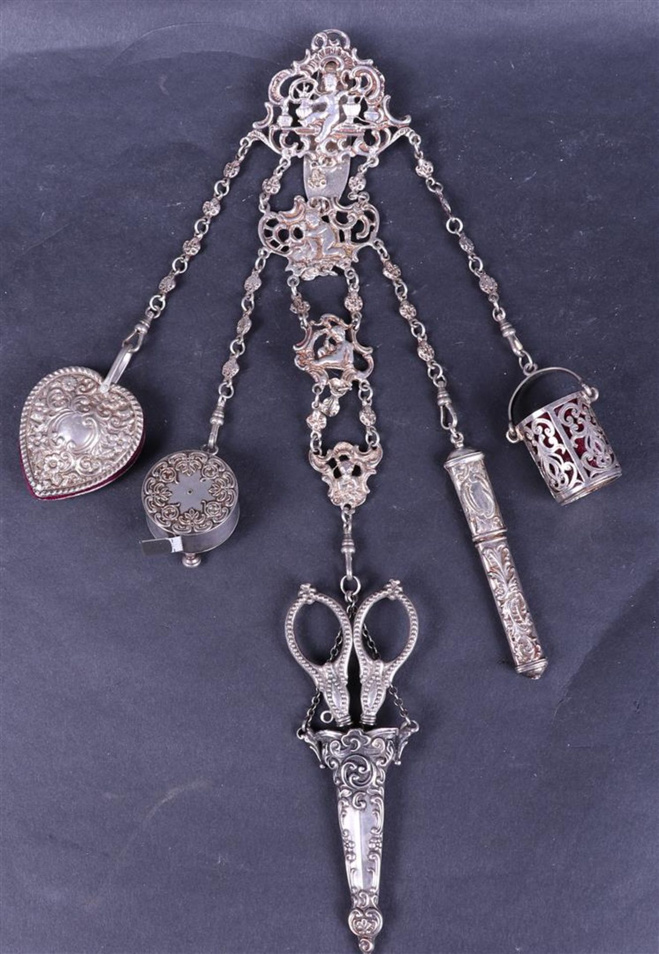 A silver chatelaine with scissors, a finger hold and various other attributes.