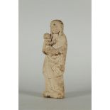 A primitive statue of Mary with Christ child, carved in sandstone.
