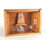 An oak diorama of a kitchen with silver miniature furniture.
